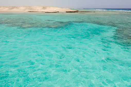 view to a amazing turquoise water and a coral reef with hills from the desert in egypt