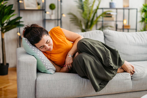 Young woman lying on the sofa and having period cramps.