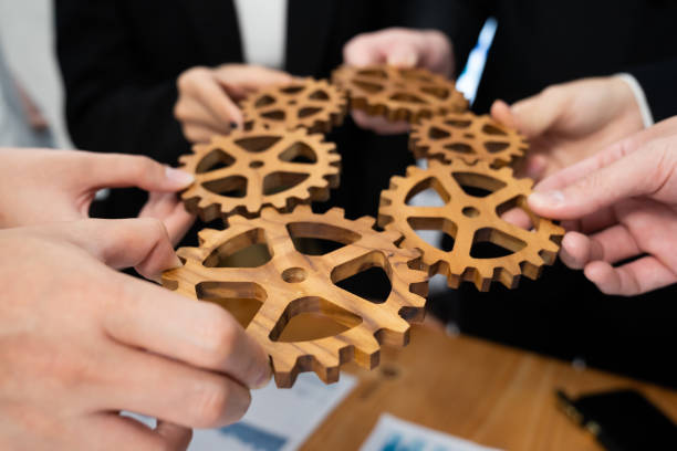 istock Closeup top view hands holding gears over table with BI reports for harmony. 1809334732