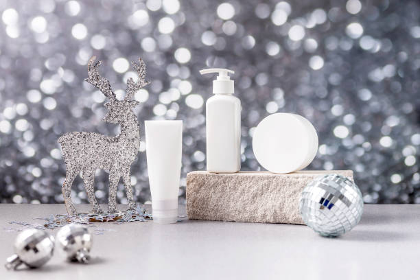 表彰台の上の化粧品の容器は、石、クリスマスの鹿、銀のボケ味の背景にクリスマスボールでできています