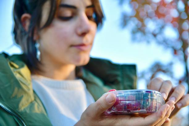 Girl eat berries from a plastic box outdoor