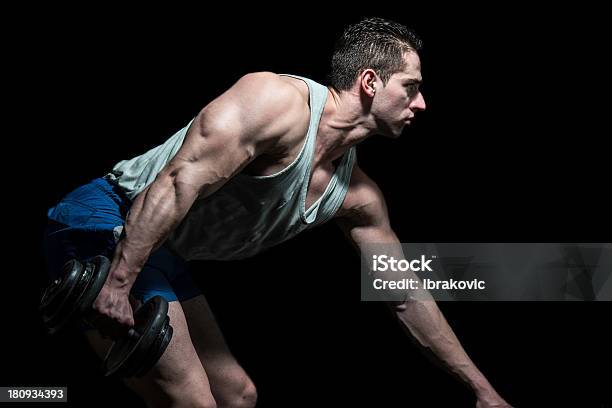 Foto de Poderoso Muscular Homem Levantando Halteres Em Fundo Preto e mais fotos de stock de Adulto