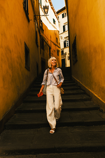 Female tourist exploring the quieter streets of the hilltop town of Cortona in the Tuscany region of Italy.