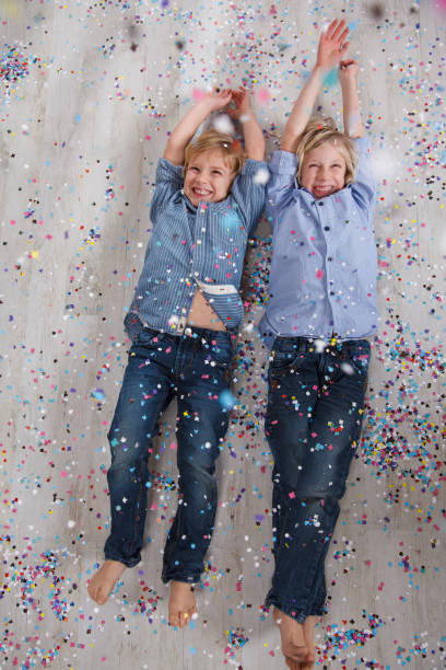istock Colorful confetti falling on two boys lying on the floor 1809352247
