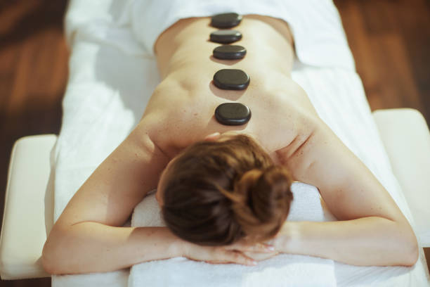 istock woman having hot stone massage and laying on massage table 1809353321