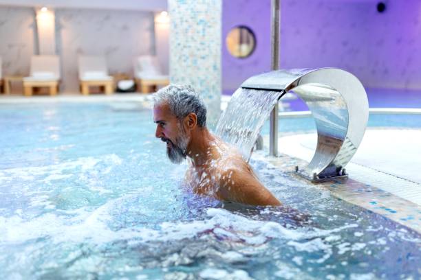 istock Man massaging his back at the pool with a water massager 1809359094