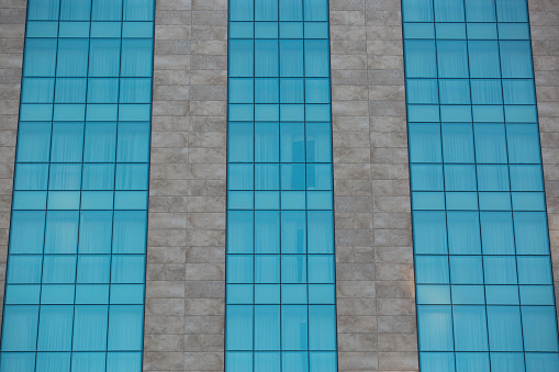 Corner of office building windows in square grid pattern reflecting sky.