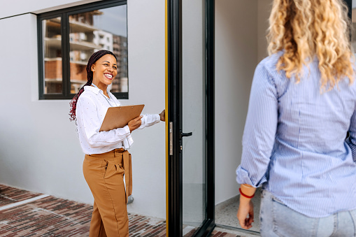 Real estate agent opening front doors of building for young couple