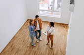 High angle view of real estate agent talking with young couple at empty apartment