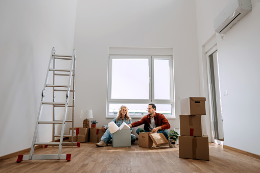 Young couple sitting on the floor at their new apartment, unpacking belongings