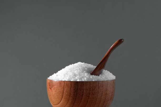 istock White table salt granules falling into a pile. Wood bowl. Gray color studio background. Condiment particles dropping. Clean cosmetic bath salt pouring footage. Closeup of grained sea salt pieces hill 1809396989