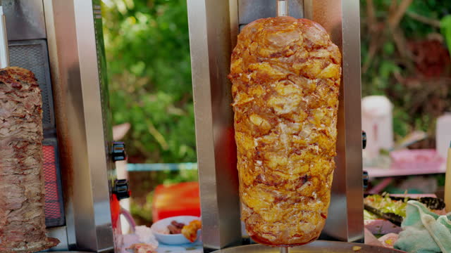 Close up shot of meats being grilled with an oven attached to a skewer at a fast-food kiosk outdoors, grilled meat for preparing donor kebab as ready-to-eat food at local restaurant.