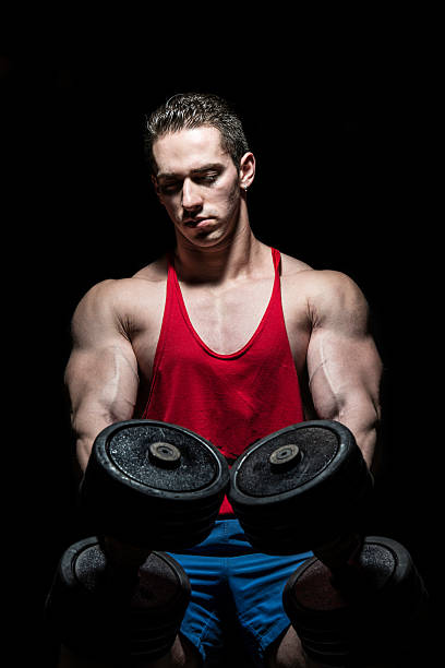 istock bodybuilder posing with dumbbell at the bench on black background 180940296