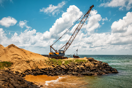 Dragline excavator working digging on the sea beach. Industrial theme