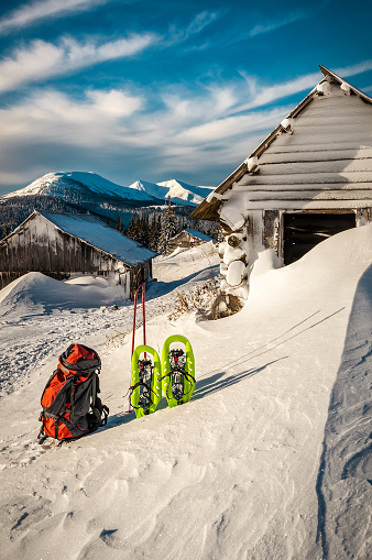 Winter tourist equipment Snowshoes, Backpack and sticks on the snow in the mountains. Tourism and travel theme