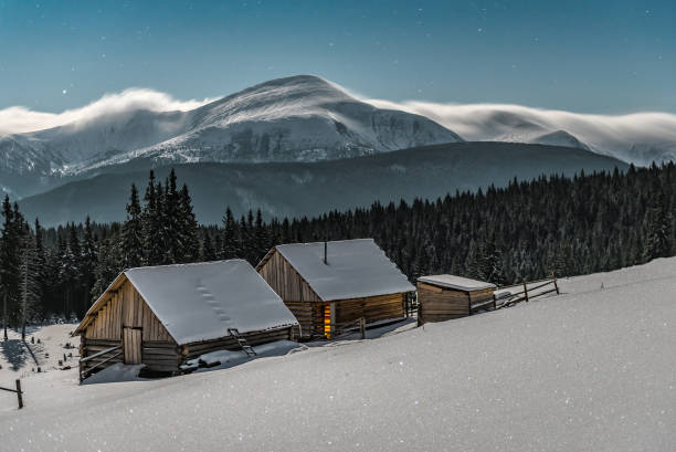 istock Two wooden log cabins under moonlight in winter Carpathian mountains 1809410803