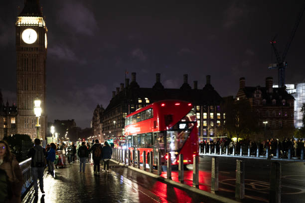 Classic London red bus navigates through a brightly lit street with Christmas decorations and busy foot traffic. Ideal for travel, holiday, or urban lifestyle themes.