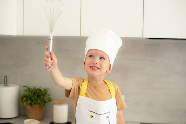 istock Little Caucasian Boy on Chef Hat Cooking in the Kitchen Home Early Education Development Apron Ingredients 1809422282