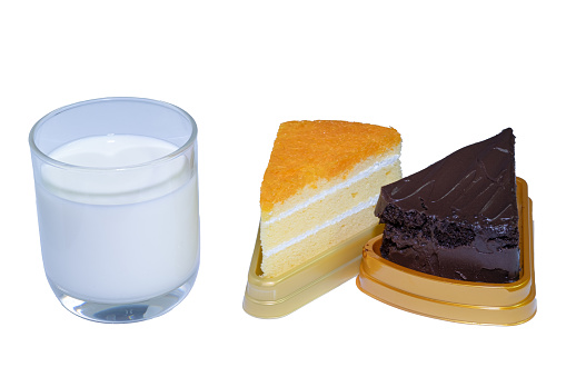 Glasses of white milk, chocolate cake and orange cake lined up against an easily distinguishable white background.