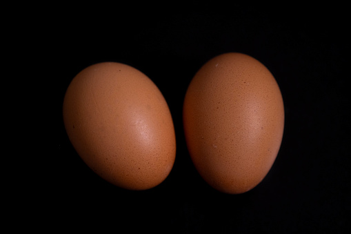 Two chicken eggs lay on an easily distinguishable black background. Can be used for cooking