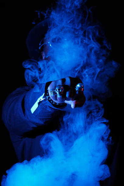 Cool male model surrounded by smoke reaching out fist with rings in dark room with blue neon light