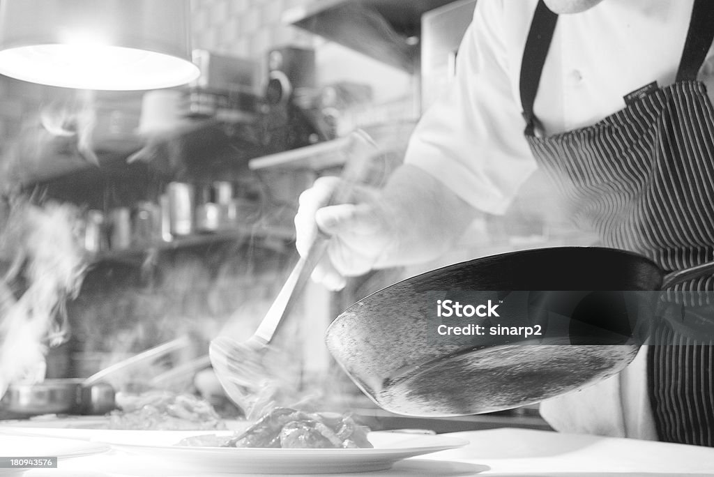 Black and white recording in the kitchen A snapshot in a kitchen with steaming pots and plates in black and white. A chef is preparing a gourmet plate. Chef Stock Photo