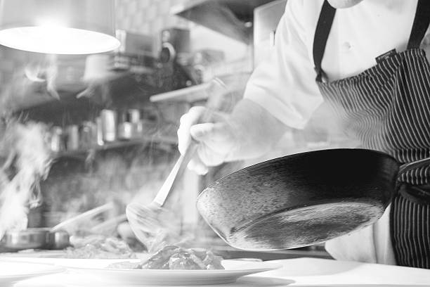 Black and white recording in the kitchen A snapshot in a kitchen with steaming pots and plates in black and white. A chef is preparing a gourmet plate. sideboard photos stock pictures, royalty-free photos & images