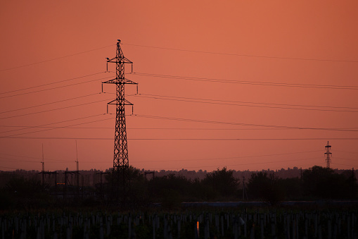 Electricity transmission pylon against orange sky