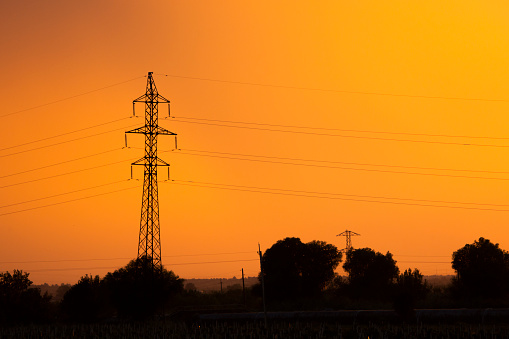 Electricity transmission pylon against orange sky