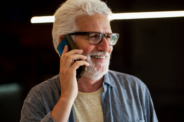 istock Mid-shot side view of senior man smiling while speaking on mobile phone 1809443331