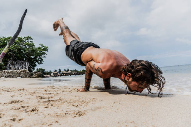 Mid adult man making handstand on the beach ripl fitness