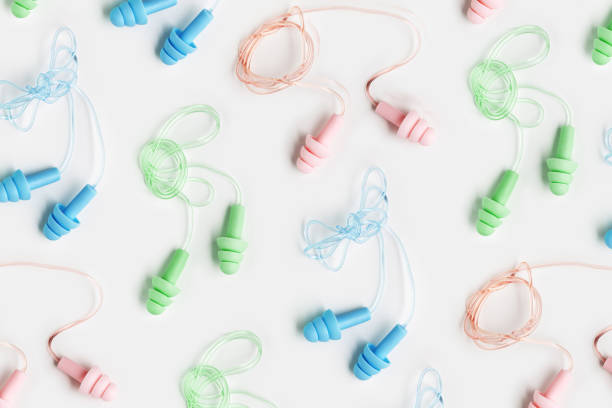 istock Reusable silicone colorful earplugs, for swim, sleep, rest as minimal trend pattern on white background. Soft, flexible ear plug on cord against noise, protect hear, close up, top view 1809459972