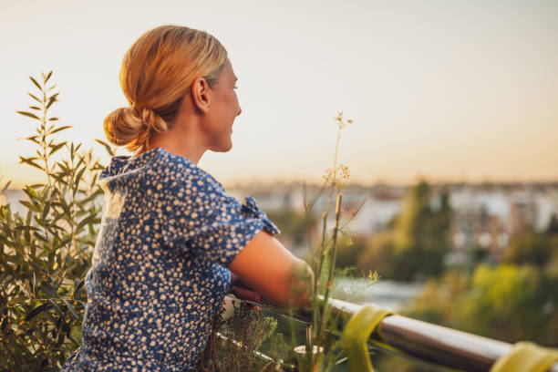 istock Woman enjoys  standing on her balcony at sunset 1809462781