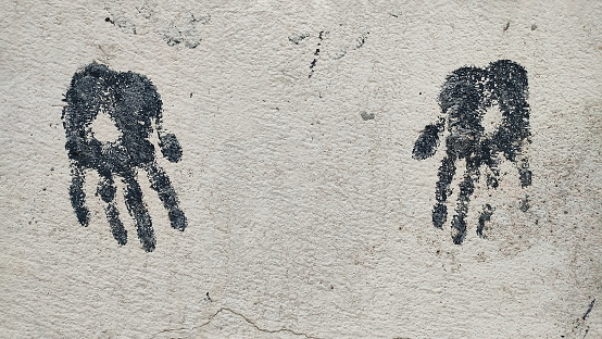 Drawing of two children's palms in black on concrete gray wall, copy space