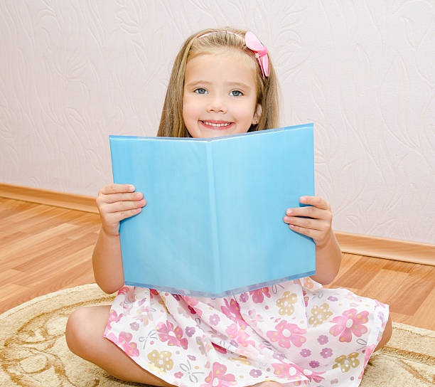 istock Cute smiling little girl reading a book 180948085