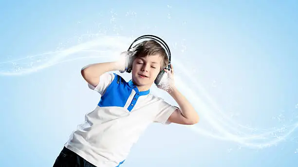 Little cute boy in headphones with eyes closed enjoying music