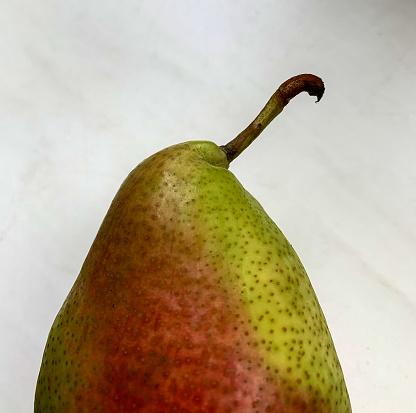 one whole green pear on a black slate board close-up, ripe fresh and juicy green pear on a slate