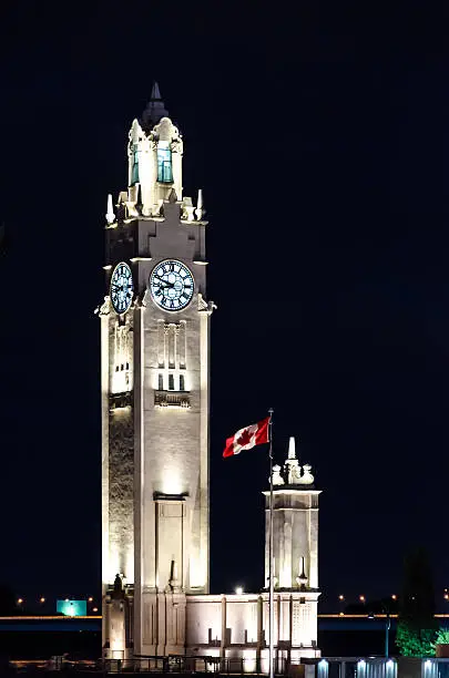 The Old-Port Clock Tower in Montreal at night wiht canadian flag.