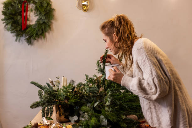 istock Young woman florist workshop makes Christmas wreath, drinks hot tea from white cup 1809522682