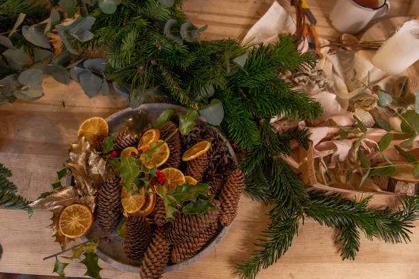 istock On wooden table in bowl are dried oranges, pine cones, tools for creating Christmas wreath 1809534240