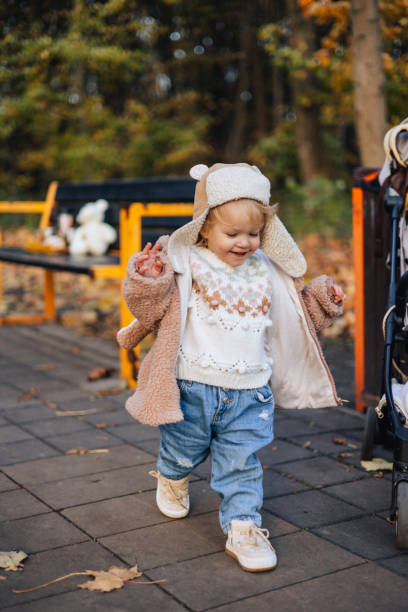 un bébé mignon et joyeux se promène dans le parc d’automne, faisant ses premiers pas - baby first steps autumn child photos et images de collection