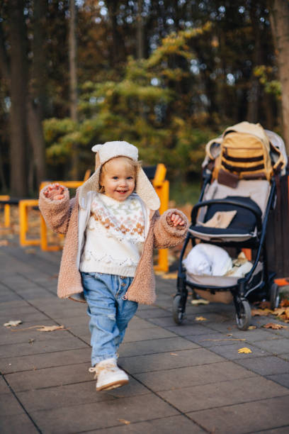 un bébé mignon et joyeux se promène dans le parc d’automne, faisant ses premiers pas - baby first steps autumn child photos et images de collection