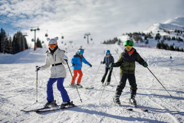 la famiglia si gode uno sci insieme in montagna in una soleggiata giornata invernale - skiing ski family friendship foto e immagini stock