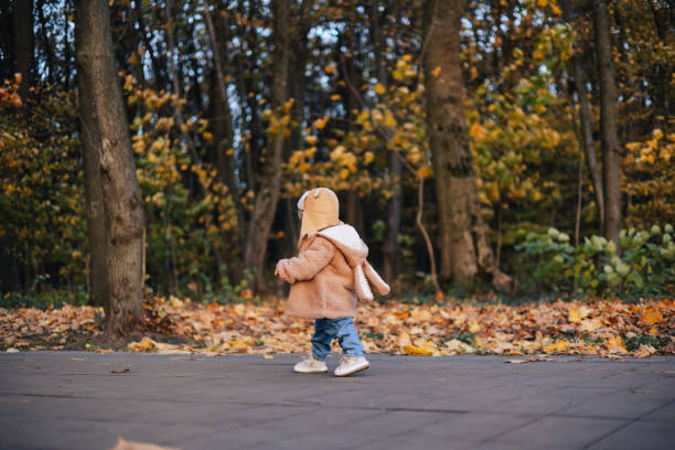 un bébé mignon et joyeux se promène dans le parc d’automne, faisant ses premiers pas - baby first steps autumn child photos et images de collection