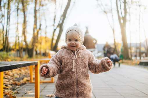 This heartwarming portrait features a cute and joyous baby girl, capturing the innocence and happiness that radiate in the enchanting surroundings of an autumn park