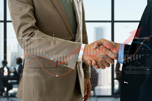 close-up of two businessmen shaking hands in a modern office. The image captures the essence of a business partnership, with the two men looking confident and determined.