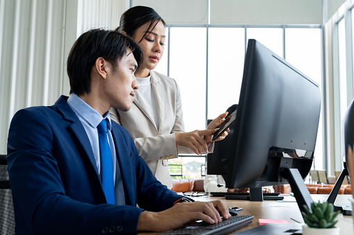 Two professionals using a desktop computer in a technology-driven workplace. This image is perfect for use in business or technology-related projects.