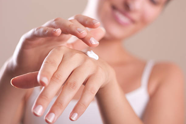 a woman applying hand lotion onto her hands - krämer bildbanksfoton och bilder