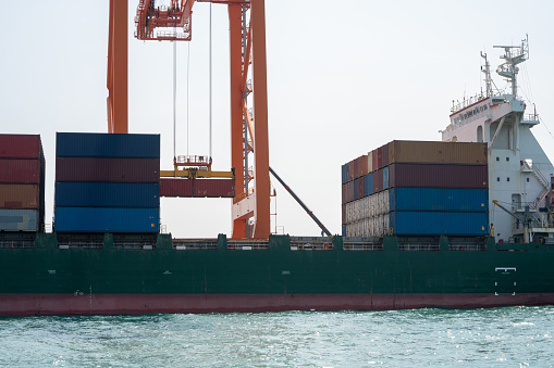 crane loading cargo container from truck to container ship in the international terminal logistic sea port concept freight shipping by ship, webinar banner forwarder mast.