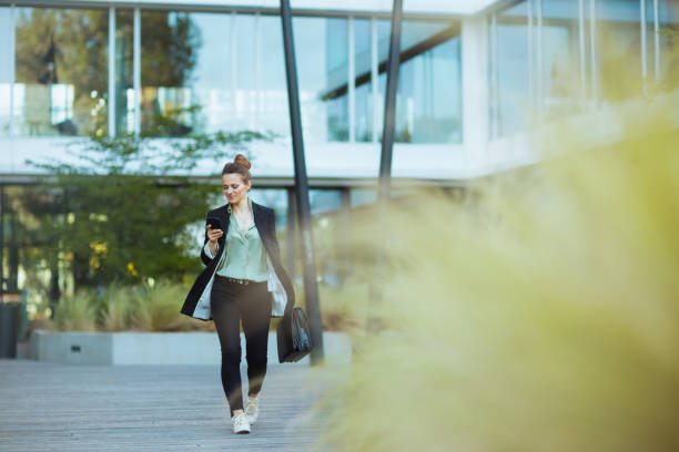 istock woman worker in business district using phone and walking 1809567744